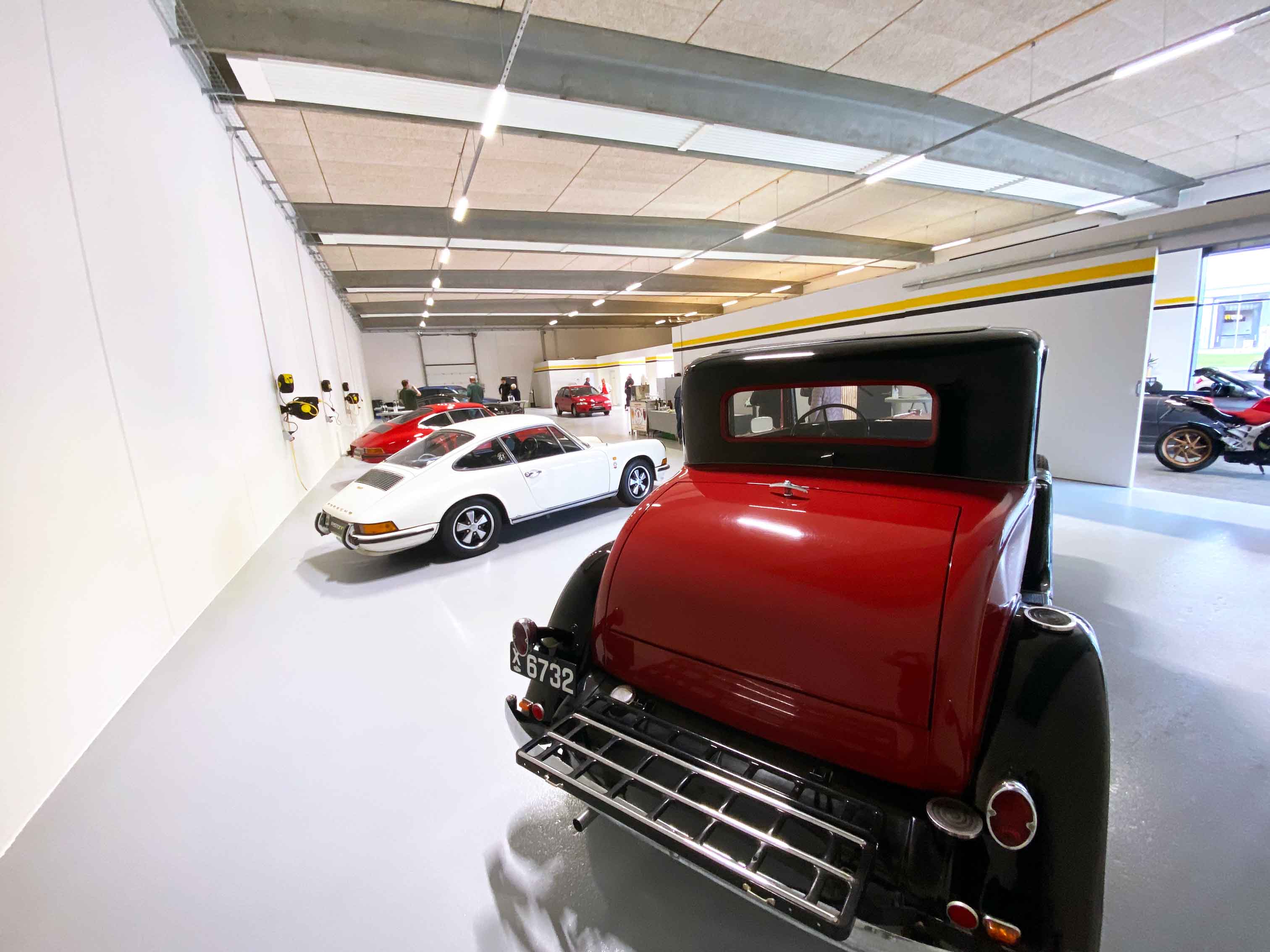 Shiny antique vehicles lined up in brightly lit showroom at RestorFX Silkeborg with branded walls