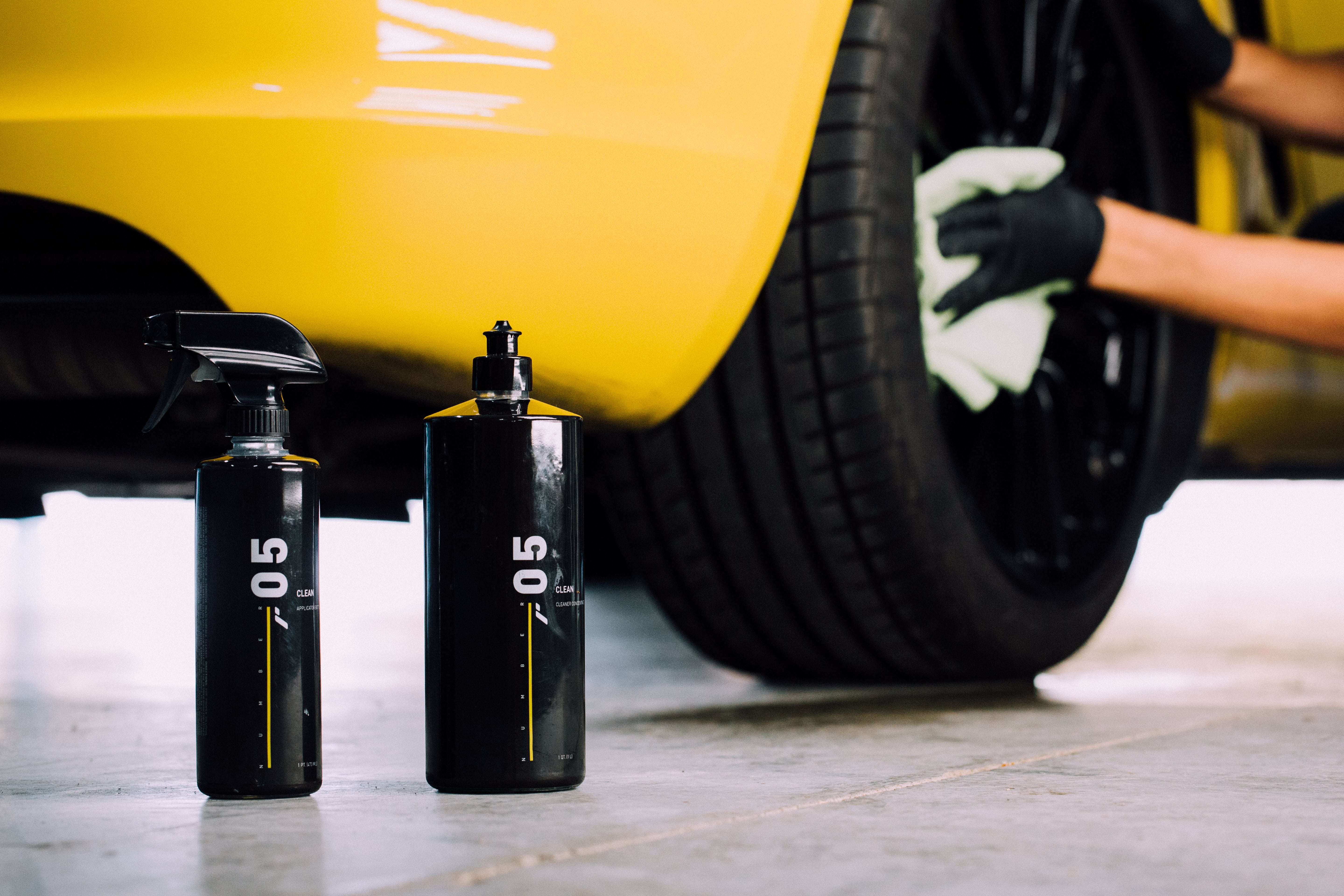 Numbers by RestorFX product and spray bottles used by a RestorFX technician detailing a bright yellow sports car